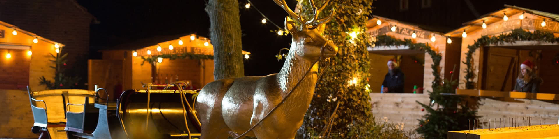 Goldener Hirsch an Schlitten gespannt auf dem Weihnachtsmarkt Beverland