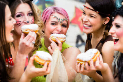 Vier verkleidete Frauen feiern Karneval und Essen Berliner