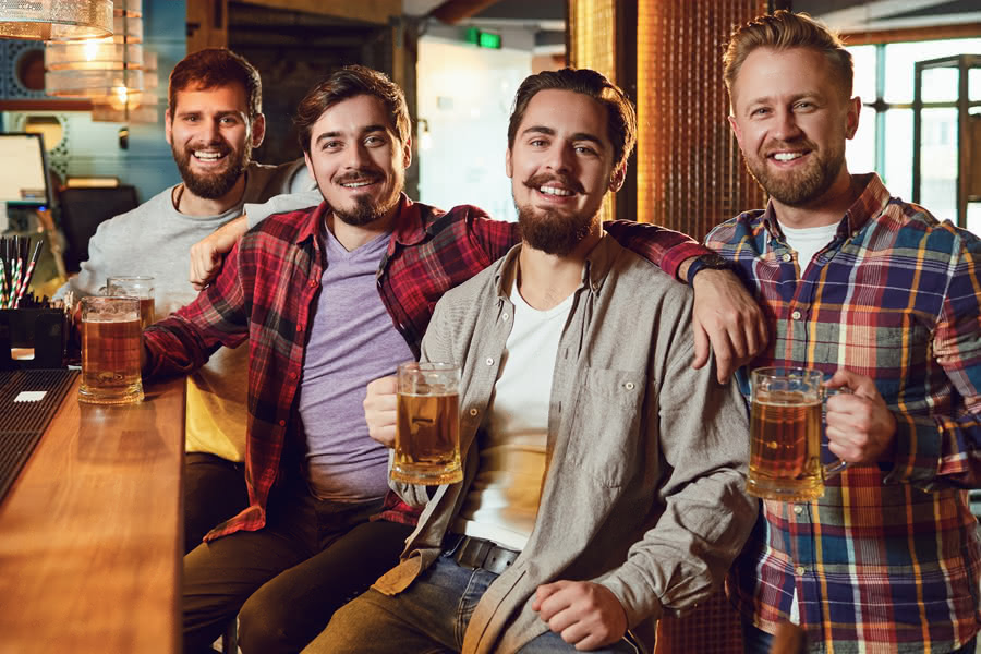 Vier Männer sitzen zusammen an einer Theke in einer Kneipe in Bremen und trinken Bier