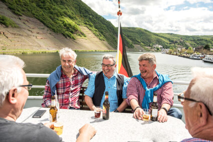 Lachende Männergruppe auf dem Deck eines Schiffes, dass auf der Mosel in Cochem fährt