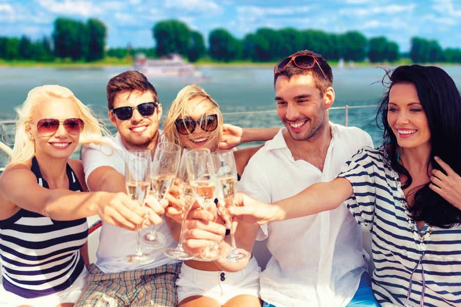 Gruppe stößt mit Sekt auf einem Schiff an