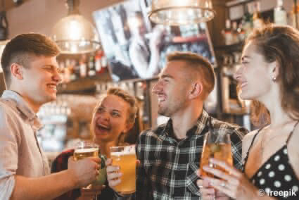eine Gruppe freunde steht zusammen an einer Bar und trinken Bier und Cocktails zusammen