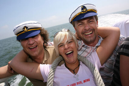 Zwei Männer mit Kapitänsmütze und eine Frau sind auf einem Schiff in Norderney