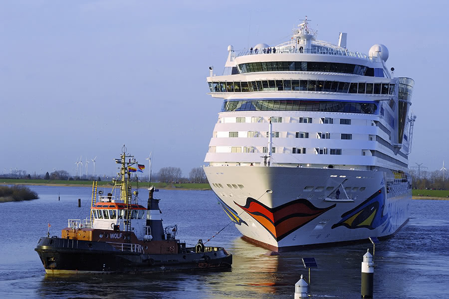 Aida-Kreuzfahrtschiff wird von eimem Schlepper in Papenburg gezogen